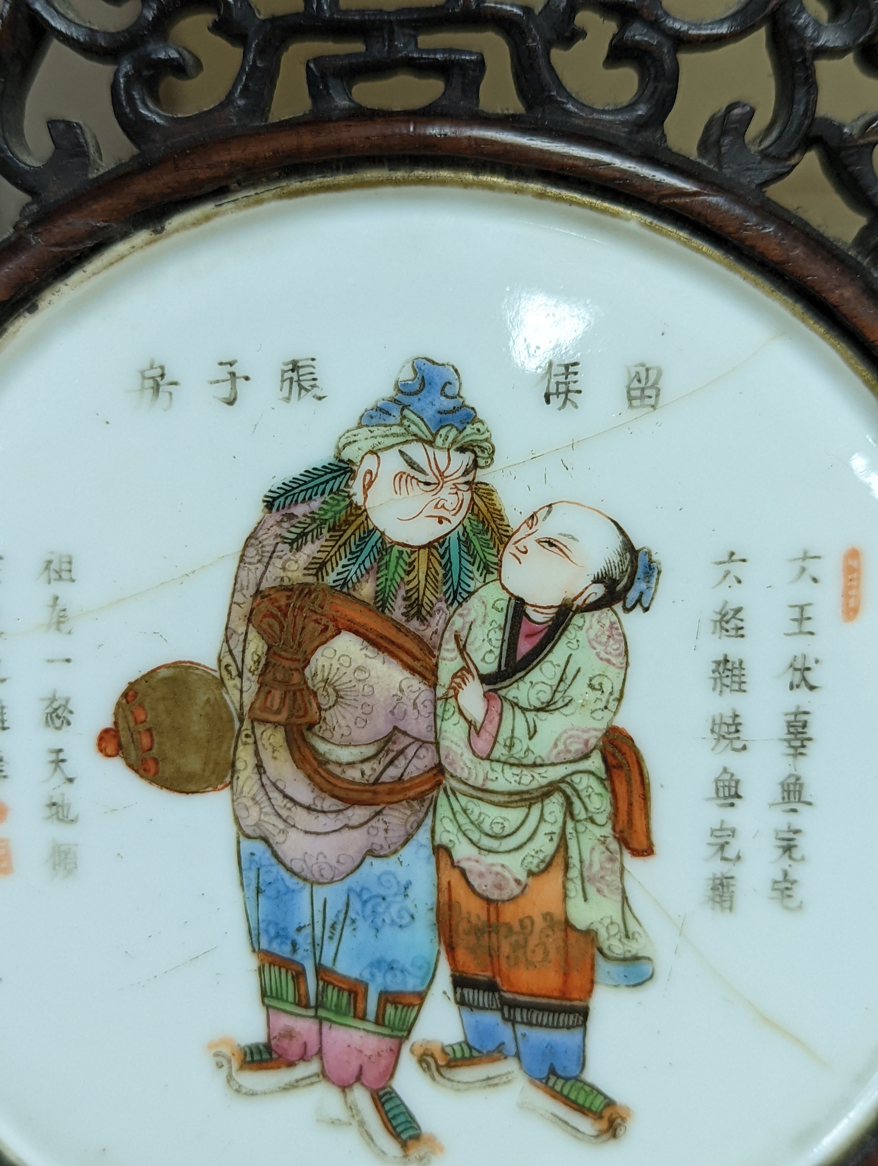 A 19th century Chinese famille rose circular plaque or cover, inset into a wood surround, cracks 15cm sq